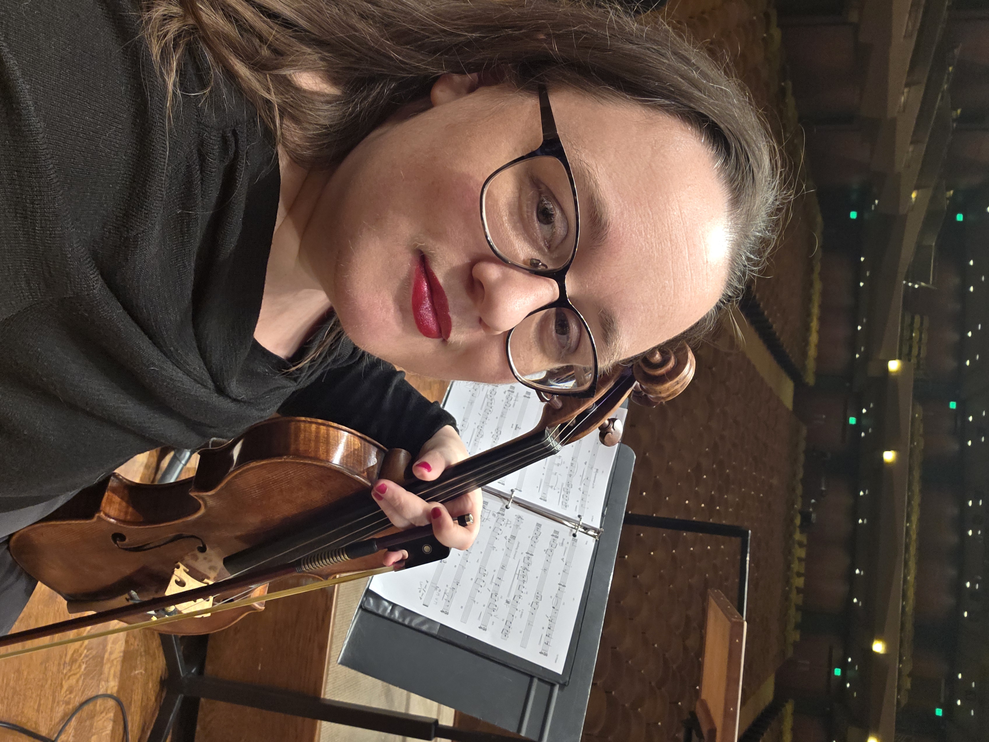 Kate on stage with violin at orchestra stand